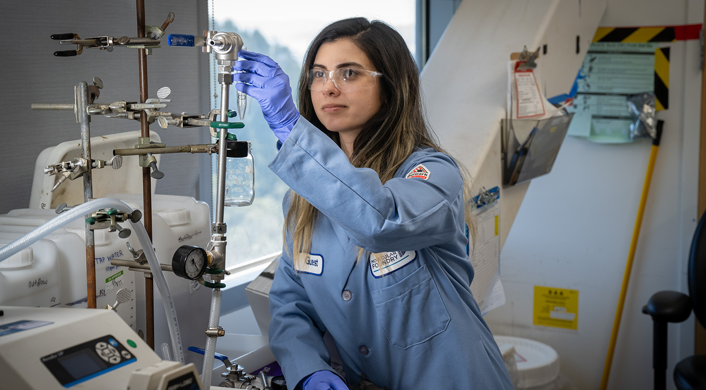 A research in blue protective safety equipment adjusts various pipes in the Molecular Foundry.