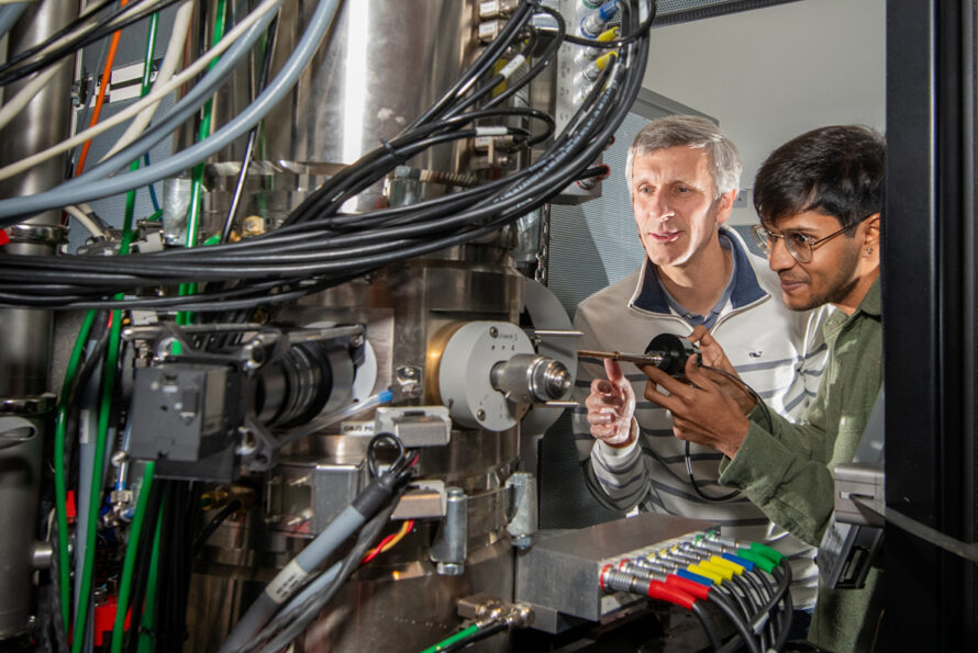 Two researchers adjusting the controls of a complex imaging instrument.
