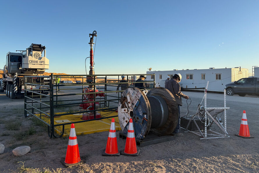 A worker stands next to an enhanced geothermal system.