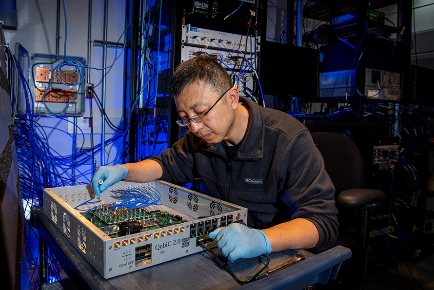 Researcher in a lab adjusting controls on a metallic device.