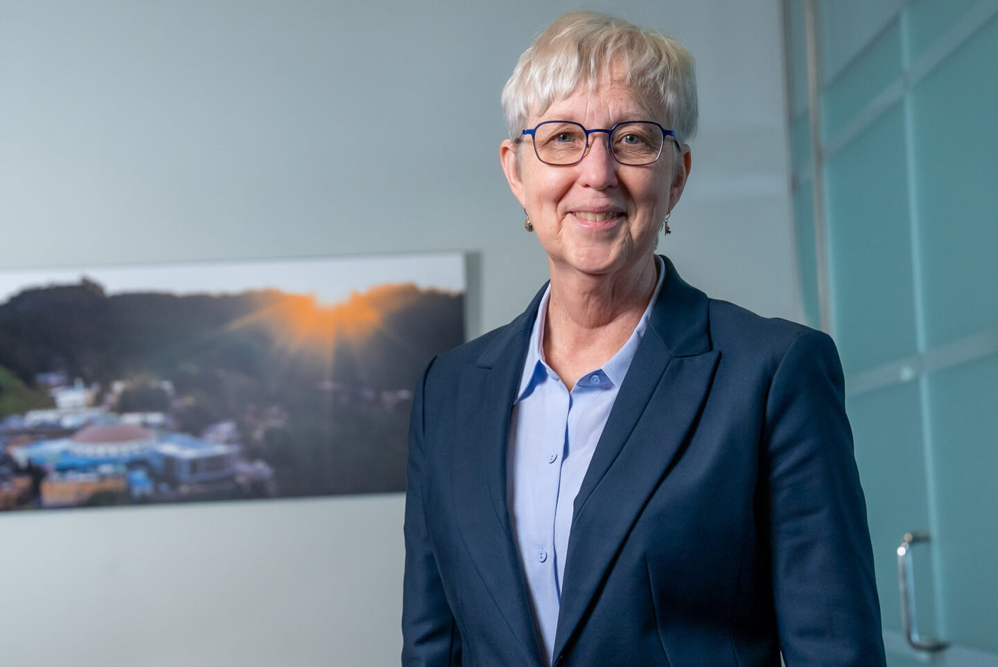 Katherine Yelick standing in front of an aerial image of Berkeley Lab.