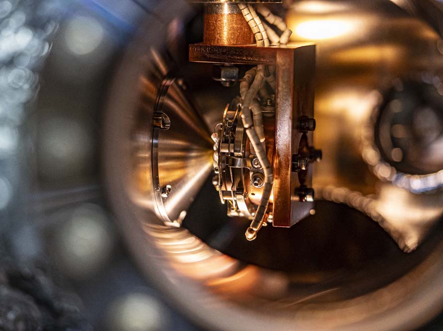 a closeup view of an amber-colored sample holding chamber with wires and coppery components, seen through a round viewing window