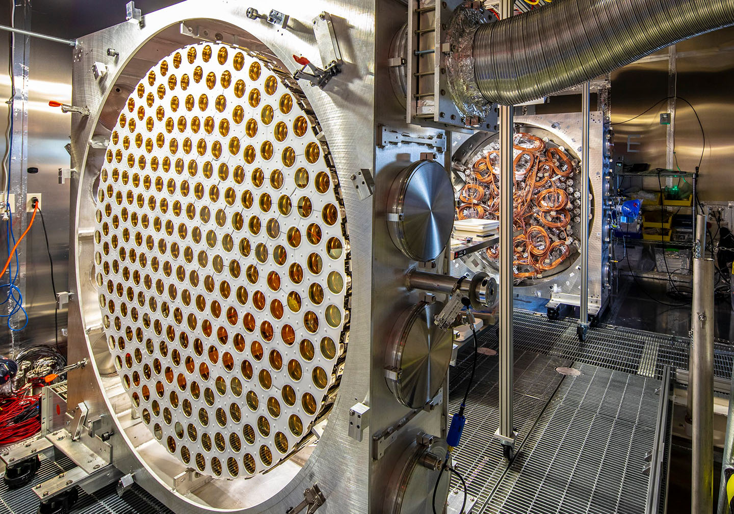 Large detector component filled with dozens of gold-colored photosensors, with cables and additional scientific equipment visible in the background.