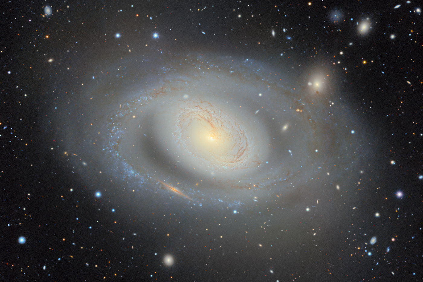 A bright spiral galaxy on a black background dotted with other stars and galaxies.