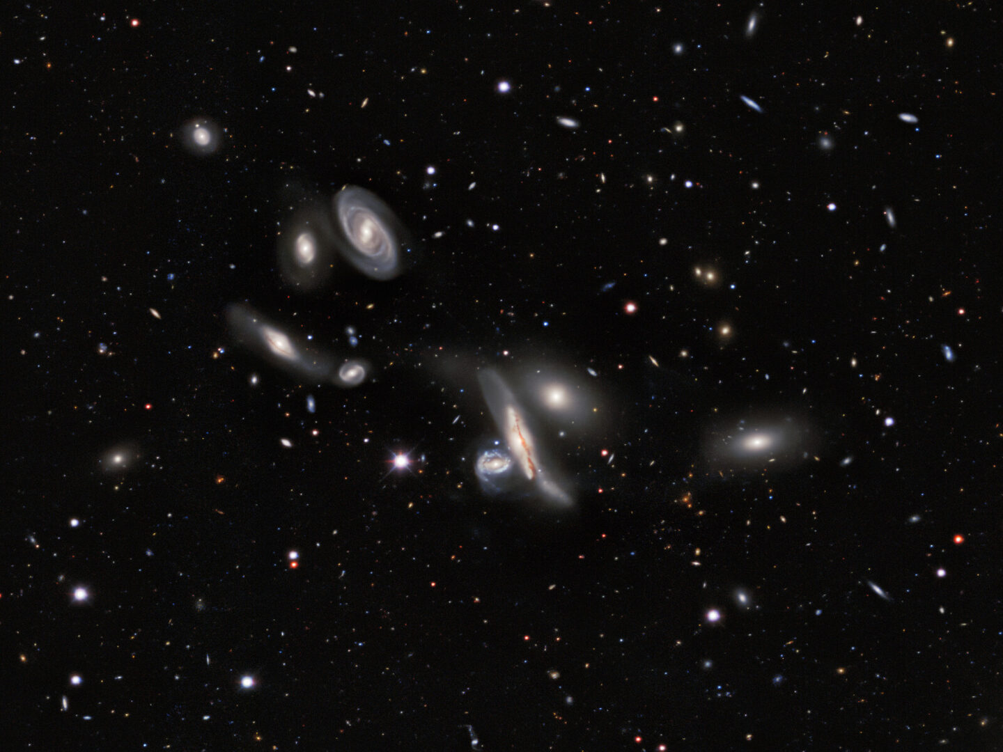 Seven bright galaxies on a black background full of points of light.