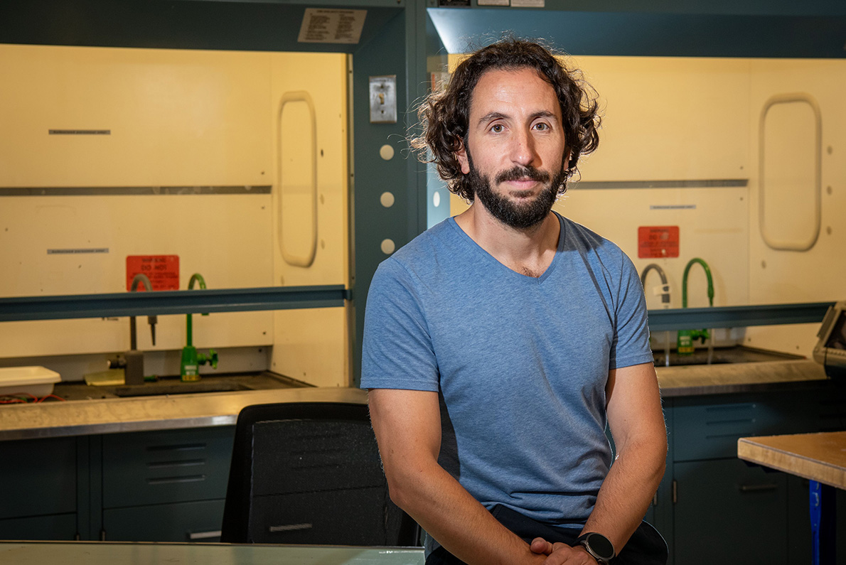 A researcher wearing a blue T-shirt sits in a research lab.
