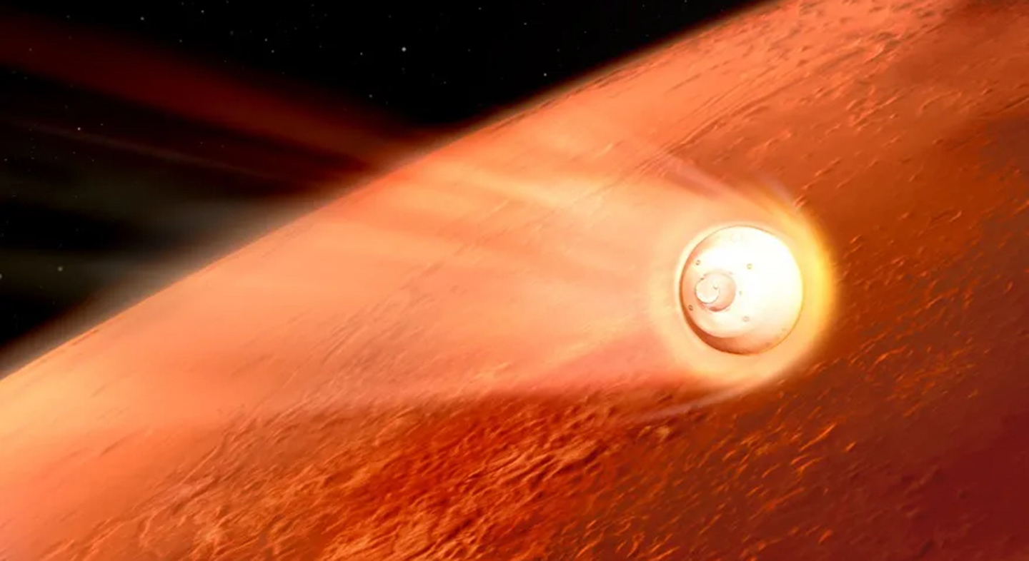 A cylindrical object surrounded by white material hovering around it and is traveling towards a giant, red, planet surface.