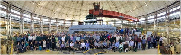 An internal view of the Advanced Light Source. A large team of reserachers poses in the middle of the room.