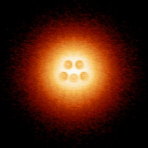 Image of an artificial atomic nucleus made up of five charged calcium dimers in the center of an atomic collapse electron cloud. (Image courtesy of Michael Crommie)