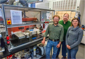 The research team, from left: Ron Zuckermann, Michael Connolly, and Gloria Olivier, standing next to their custom peptoid-making robot, RONDA. 